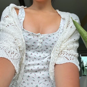 Vit stickad bolerotopp från Nadine - Supersöt vit stickad bolerotopp från Nadine, made in Italy. Tjockt garn med vågigt mönster och hålstickade detaljer, kort modell med vida ärmar. Perfekt att slänga över ett linne eller klänning för en extra touch. Säljs utan linne.