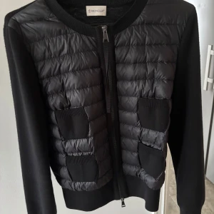 Moncler cardigan svart  - Säljer nu min fina svarta cardigan från moncler. Köpt på deras hemsida förra sommaren 2024 nypris, 9505kr. Har kvar allt och allt medföljer vid köp. Kvitton och äktenhetsbevis finns så kan 100% garantera att den är äkta. Den är sparsamt använd och har inga tecken på användning. Kontakta för fler bilder eller frågor!🩷🩷