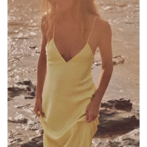 Ljusgul långklänning med öppen rygg - Superfin ljusgul långklänning med smala axelband och djup v-ringning. Klänningen har en snygg öppen rygg med tunna banddetaljer. Säljs då jag tyckte den var för kort för mig (jag är 165cm). Helt oanvänd, endast testad🫶🏼 stl xs 