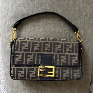 Fendi Baguette (INTE äkta) - Oäkta Fendi Baguette axelväska. Väskan har guldfärgade metalldetaljer, svart skinnrem och magnetlås framtill. Insidan är fodrad med svart tyg och har innerfack med dragkedja. Inköpt secondhand