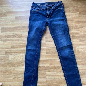 Jack & Jones Skinny Liam jeans blå - Säljer ett par mörkblå skinny jeans från Jack & Jones, modell Liam. Jeansen har klassisk femficksdesign, smal passform och snygga kontrastsömmar. Tillverkade i stretchigt denim för extra komfort. Perfekta för dig som gillar en tight look.