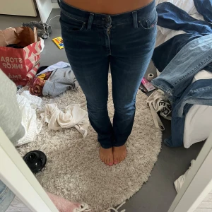 Diesel Bootzee bootcut jeans blå - Snygga blå bootcut jeans från Diesel, modell Bootzee. Jeansen har regular waist, slim passform upptill och lätt utsvängda ben. Stretchigt denimtyg som sitter skönt och formar sig efter kroppen. Klassisk femficksmodell och diskreta detaljer.