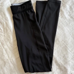 Svarta leggings från Adidas - Svarta tights från Adidas med vit logga på låret och bred resår i midjan med diskret Adidas-tryck. Mesh material, se bild 2. Nyskick! Storlek XS       🌸✨ 