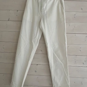 Vita linne byxor från Selected Homme - Snygga vita byxor från Selected Homme med dragsko i midjan och avslappnad passform. Byxorna har fickor i sidorna och en bakficka, tillverkade i mjukt bomullsmaterial. Perfekta för en clean och stilren look.Storlek är oklart vid intresse kan jag mät dom!