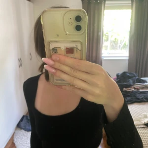 Svart croppad långärmad topp SHEIN - Svart croppad långärmad topp från SHEIN med rundad, bred urringning. Toppen har ribbad struktur och sitter tight mot kroppen. Perfekt att styla med höga jeans eller kjol för en trendig look.