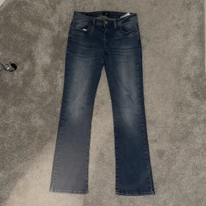 Blå bootcut jeans från LTB, W28 L32 - Snygga blå jeans från LTB i modellen valire. Jeansen har fem fickor, bootcut  passform och subtila slitningar framtill. Tillverkade i mjukt denimtyg som sitter skönt hela dagen. Perfekta för dig som gillar en tidlös look.