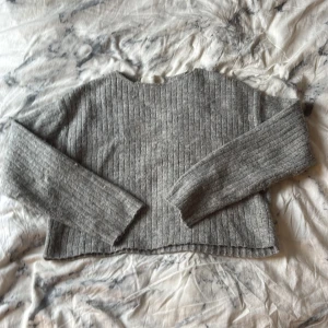 Grå ribbstickad tröja från H&M - Mysig grå ribbstickad tröja från H&M med lång ärm och rund hals. Perfekt för lager-på-lager och chill dagar. Tröjan har en klassisk passform och är tillverkad i ett mjukt stickat material som håller dig varm under kyliga dagar.