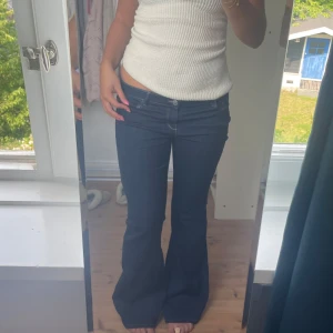 Mörkblå bootcut jeans med låg midja - Säljer ett par mörkblå jeans med snygg bootcut och låg midja. Jeansen har klassiska fickor fram och bak, och är i ett stretchigt denimtyg som sitter skönt. Perfekta om du gillar 00-talsvibbar och vill ha en cool siluett. Använda 2 gånger!