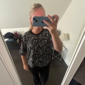 Svartvit mönstrad blus med trekvartsärm - Svartvit blus med abstrakt mönster och rund halsringning. Modellen är loose fit med trekvartsärmar och mjukt, lätt material. Perfekt för dig som gillar en chill och trendig look.