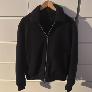 Marinblå overshirt med dragkedja - Stilren mörkblå overshirt med klassisk krage och silverfärgad dragkedja framtill. Jackan har en clean look, raka linjer och ribbade muddar vid ärmslut och midja. Perfekt för dig som gillar minimalistisk stil och vill ha en jacka som funkar till det mesta.