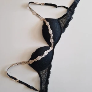 Svart intimissimi bh - Snygg svart bh från intimissimi som inte säljs längre. Axelbanden är dekorerade med beige spetsblommor som ger en extra touch. Perfekt för dig som gillar feminina och trendiga underkläder.