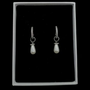 Glittriga örhängen med pärldroppar - Snygga örhängen i silverfärg med glittriga stenar på ringen och hängande droppformade pärlor. Ovanför pärlan sitter en liten stjärndetalj som ger extra charm. Perfekta för dig som vill sticka ut med en elegant och trendig look.