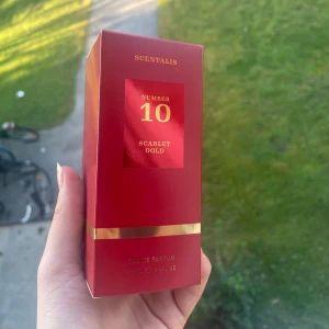Scentalis Number 10 Scarlet Gold parfym - Säljer en lyxig parfym från Scentalis, Number 10 Scarlet Gold. Flaskan rymmer 100 ml Eau de Parfum och kommer i en snygg röd och guldig förpackning. Perfekt för dig som gillar eleganta och exklusiva dofter.
