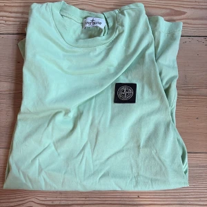 Mintgrön t-shirt  - Fräsch mintgrön t-shirt  med klassisk rund hals och korta ärmar. På bröstet sitter den ikoniska svarta patchen med loggan. T-shirten är gjord i mjuk bomull och har en clean, loose passform som är chill och enkel att styla.