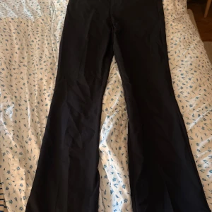 Svarta bootcut kostymbyxor från BikBok - Svarta bootcut-byxor från BikBok i storlek 34. Byxorna har en klassisk passform med utsvängda ben och hällor för bälte. Snygga och stilrena, perfekta till sneakers eller boots.
