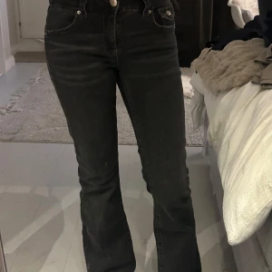 Svarta bootcut jeans från Gina Tricot - Mid/low waisted. Snygga svarta jeans från Gina Tricot i bootcut-modell med klassiska fem fickor och coola ficklock bak med silverfärgade knappar. Jeansen har normal passform och är tillverkade i jeansmaterial med lätt stretch. Perfekta för dig som gillar en retro vibe och vill ha lite utsvängda ben. Använda men nästa sol nya 🥰🥰