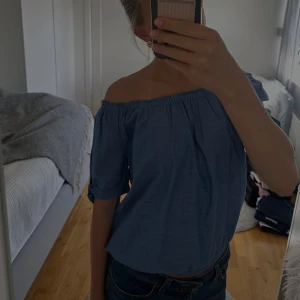 Blå offshoulder topp från H&M - Snygg blå offshoulder topp från H&M med korta ärmar och resår både upptill och nertill. Prislappen kvar. Ärmarna har en söt knytdetalj som ger extra stilpoäng. Passar perfekt både till jeans och kjol!