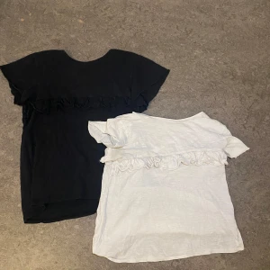 Svart och vit topp med volangdetalj - Två enkla toppar i svart och vitt med kort ärm och volangdetalj tvärs över bröstet. De har rund halsringning och är gjorda i skön bomull köpt på zara. säljs tillsammans 