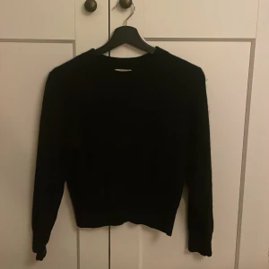 Svart kashmirtröja från Cashmere by T - Säljer en elegant svart kashmirtröja från Cashmere by T. Tröjan har en klassisk design med långa ärmar och rund halsringning. Perfekt för att hålla dig varm och stilren under kyligare dagar.