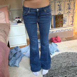 Blå bootcut jeans från Monki - Snygga blå jeans från Monki med bootcut-modell och klassisk femficksdesign. Jeansen har hög midja och är tillverkade i stretchig denim som sitter skönt. Perfekta för dig som gillar en retroinspirerad look med utsvängda ben.
