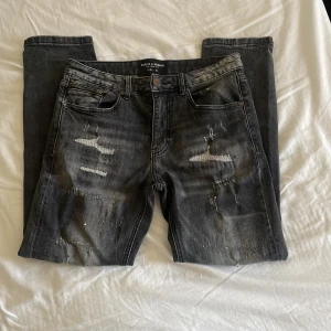 Grå slitna jeans Supply & Demand XS - Säljer ett par grå jeans från Supply & Demand med coola slitningar och distressed detaljer framtill. Jeansen har fem fickor, raka ben och klassisk knappgylf. Helt nya och toppskick🌟