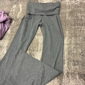 Grå mjukisbyxor från SHEIN - Grå mjukisbyxor från SHEIN med bred, hög midja och utsvängda ben. Byxorna är gjorda i mjukt och stretchigt material, perfekta för en chill och avslappnad stil. Passformen är loose och de har en enkel, stilren look utan detaljer.