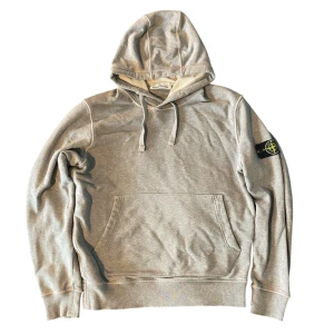 Grå hoodie från Stone Island  - Snygg grå hoodie från Stone Island med klassisk patch på vänster ärm. Enkel och stilren design som funkar till det mesta. Bra skick förrutom små revor på ena armen (bild 5) tveka inte på att skriva vid frågor.
