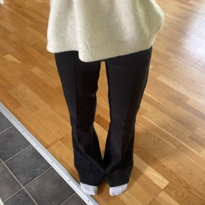 Svarta kostymbyxor från Gina Tricot - Snygga svarta kostymbyxor från Gina Tricot i klassisk modell med pressveck framtill. Byxorna har hög midja och raka ben med en lätt bootcut-känsla. Perfekta för en clean och stilren look. Materialet känns mjukt och följsamt. Skriv för fler bilder!