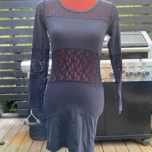 Svart spetsklänning från R&D small - Svart klänning med långa ärmar och spetsdetaljer på axlar, mage och ärmar.  Längd: 82 cm Bystvidd: 40 cm.  Inga bilder när den sitter på mig! Katter finns i hemmet! Kan ej skicka med UPS!