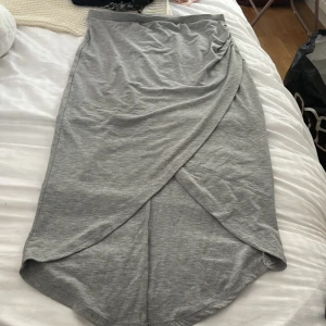 Grå omlottkjol i bomull - Snygg grå långkjol med omlott-design och mjukt fall. Kjolen är enkel men trendig och passar perfekt till sneakers eller sandaler. Tillverkad i skön bomull.