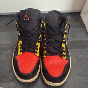 Nike Air Jordan 1 Mid röd/gul/svart - Säljer mina air jordans, tidigare köpta från Foot locker. Dem är väl använda men med rätt kärlek tror jag att dem går att rusta upp lite. Skorna är i storlek 40.