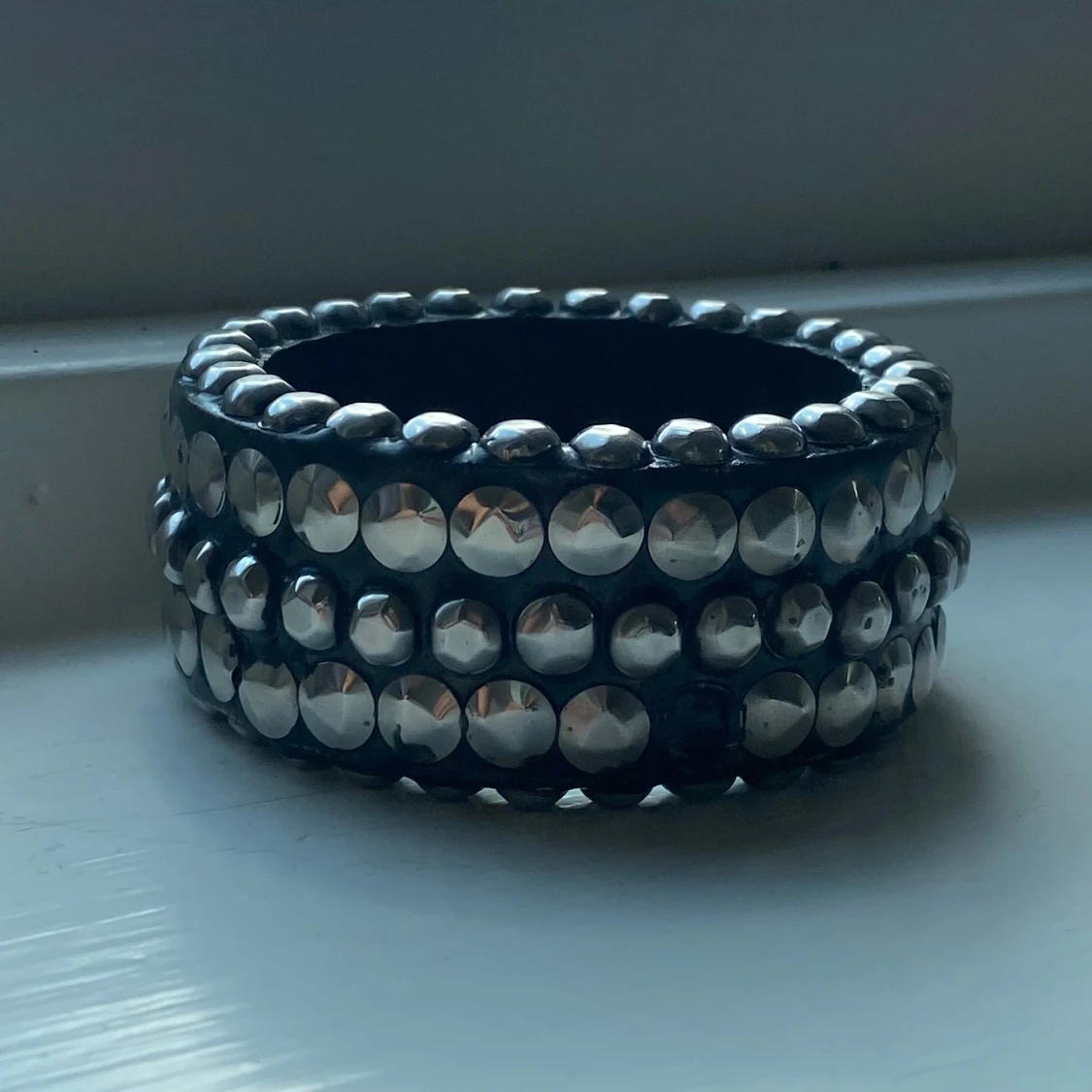 Brett svart armband med silvriga nitar/stenar