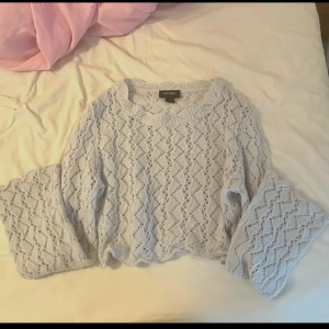 Ljus stickad tröja från Monki - Supersöt ljus stickad tröja från Monki med genombrutet mönster och vida ärmar. Perfekt för lager-på-lager och ger en chill vibe till din outfit. Tröjan har rund halsringning och är lätt croppad för en trendig look.