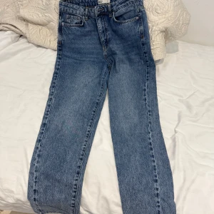 Blå raka jeans med hög midja - Klassiska blå jeans med rak passform och hög midja. Jeansen har fem fickor och stängs med dragkedja och knapp. Mom jeans från Gina tricot