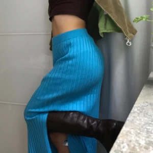Blå ribbad långkjol med slits - Säljer en ljusblå ribbstickad långkjol med hög midja och snygg slits på sidan. Kjolen har en tight passform och är perfekt för dig som vill sticka ut med färg. Superenkel att styla med boots eller sandaler.
