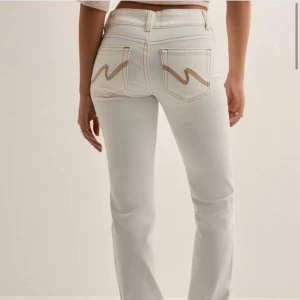 Vita low waist bootcut jeans - Vita lågmidjade jeans med bruna sömmar. Storlek 44. Använt en gång. Har andra vita jeans så därför behöver jag inte dessa, men dom är väldigt fina på! Orginalpris när jag köpte dom från Nelly var 699kr.