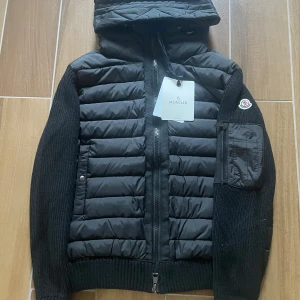 Ny Moncler Cardigan med luva - Moncler Cardigan i nyskick - aldrig använd. Storlek M men kan passa S. Väldigt clean och sällsynt modell. Den är gjord av skönt material och sitter sjukt bra på kroppen. Passar alla outfits och matchar med alla färger. Kan frakta samt mötas upp!