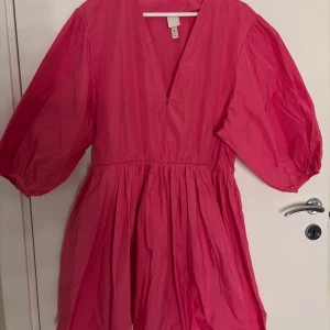 Rosa kortklänning - Superfin rosa kortklänning från H&M med v-ringning och voluminösa puffärmar. Klänningen har en luftig kjol och markerad midja, perfekt nu till sommaren💕💕storlek 42 men passar absolut en 38/36