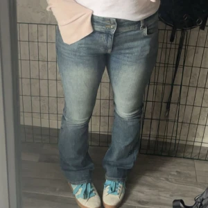 bootcut jeans  - Säljer ett par blå bootcut jeans från Bershka med snygg tvätt och klassiska fem fickor. Jeansen har medel till låg midja, dubbla knappar och är tillverkade i jeansmaterial. 