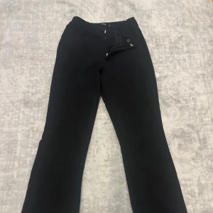 Svarta bootcut byxor från BikBok - Svarta bootcut byxor från BikBok i klassisk modell. Byxorna har normal passform, dragkedja och knapp framtill samt bälteshällor. Perfekta till sneakers eller boots för en clean look. 