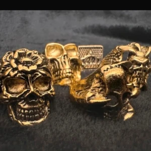 Set med 5 guldfärgade dödskalleringar – alternativ statementstil - Nya  -  Säljer ett set med fem nya ringar i guldfärgad metall med olika dödskalledesigner – blommor, korslagda ben och texturer. Varierande storlek (innerdiameter ca 1,8–2,5 cm, höjd 2–3 cm), så de kan bäras på olika fingrar. Perfekta för dig som gillar punk, goth eller alternativ stil. Priset är fast – ingen prutning – men bundlerabatt ges. Rensar smyckeslådan, så kolla gärna mina andra annonser också!  