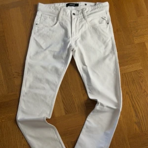 Vita slim fit  jeans från Replay - Snygga vita jeans från Replay med power stretch för extra komfort. Modellen är slim fit med klassisk femficksdesign och detaljerade sömmar. Perfekta för dig som vill ha en fräsch och stilren look. Materialet är stretchigt jeans och färgen är helt vit. Jeansen är endast använda en gång och kom tyvärr med en mindre rosa fläck när de köptes.  W32 L34