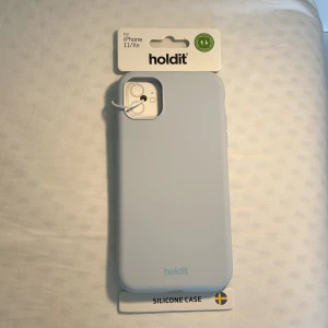 Ljusblått mobilskal Holdit i silikon - Snyggt ljusblått mobilskal från Holdit, gjort i mjukt silikon som ger ett stilrent och modernt intryck.Säljer ett stilrent och skyddande mobilskal från Holdit, passar till iPhone 11/XR. Skalet är helt oanvänt och i nyskick.