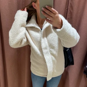 Vit teddyjacka med krage - Mysig vit teddyjacka med stor krage och rak passform. Jackan är fluffig och har långa ärmar, perfekt för vår/höst/tidig vinter! Jackan är från Kappahl och är använd sparsamt under en säsong. 