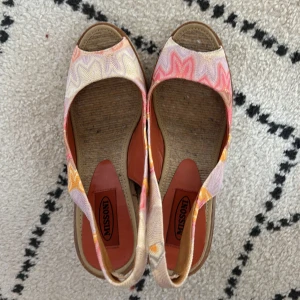 Missoni kilklackade sandaler i pastell - Intressekoll på mina färgglada sandaler från Missoni med kilklack i flätad jute. Ovandel i tyg med vågigt mönster i rosa, lila, gult och beige. Öppen tå och slingback-rem för en somrig vibe. Perfekta för dig som vill sticka ut med stil och komfort. Kontakta gärna mig om du är intresserad!💕