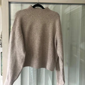 Beige stickad tröja & Other Stories - Fin beige stickad tröja från & Other Stories med hög krage. Den har breda ribbade muddar vid hals, ärmslut och nederkant. Storlek S. (Tröjan är använd ich har synliga noppror, därav nedstänkt pris) inköpspris: 550 kr. Säljs för: 300 kr