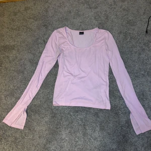 Ljuslila långärmad topp Gina Tricot - Supersöt ljuslila långärmad topp från Gina Tricot med utsvängda ärmslut och rundad urringning. Sitter tajt och är gjord i mjuk bomullsmix, perfekt att styla med jeans eller kjol för en chill look.