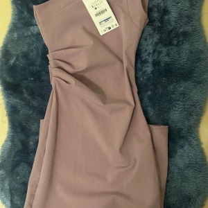 Ljuslila långklänning från Zara - Säljer en snygg långklänning från Zara i en ljuslila ton. Klänningen har oneshoulder-design med smal axelrem och cool rynkdetalj i sidan. Materialet är mjukt och lätt, perfekt för sommarkvällar. Enkel men trendig look som sticker ut. Du kan hitta mer på min sida 