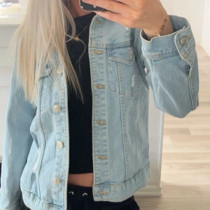 Ljusblå jeansjacka - Snygg ljusblå jeansjacka med knappar framtill och två bröstfickor. Jackan har en klassisk design med långa ärmar och en normal passform. Perfekt för vår och sommar! Lite liten för mig som brukar ha xs, lite sliten i nacken men inget som syns när man har den på sig🫶🏼