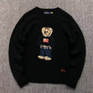 Svart tröja med björnmotiv från Ralph Lauren - Säljer en svart tröja från Ralph Lauren med ett ikoniskt björnmotiv på framsidan. Tröjan har långa ärmar och en rund halsringning. 
